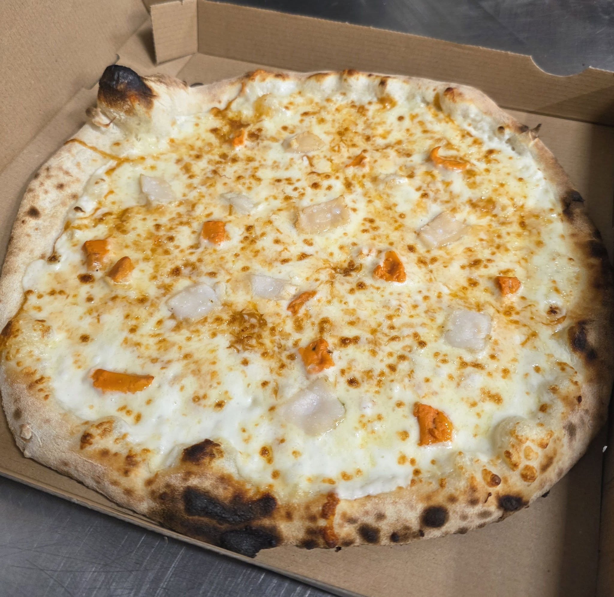 Pizza sortant du four à bois de La Coquetière, base crème